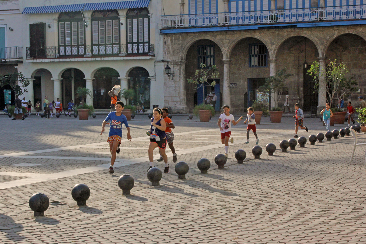 Photo of school children running around the Plaza Vieja for their morning exercise, in Havana, Cuba.